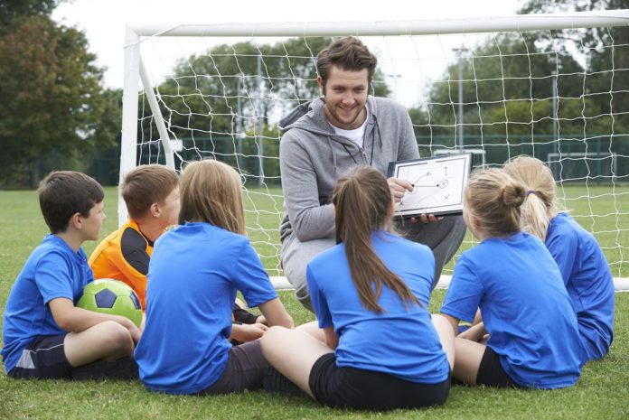 Coach Giving Team Talk To Elementary School Soccer Team